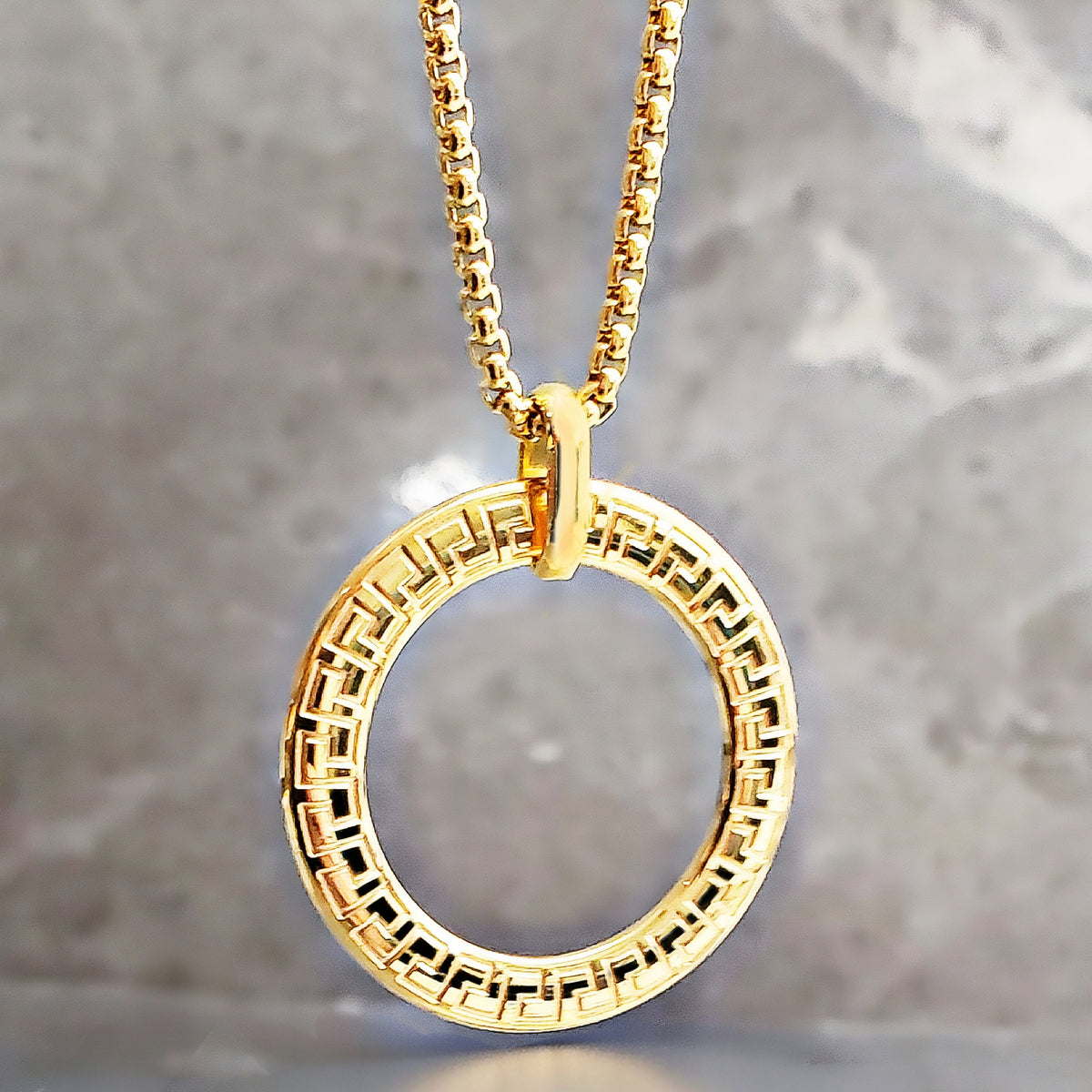 Amuleto con anillo de greca dorada